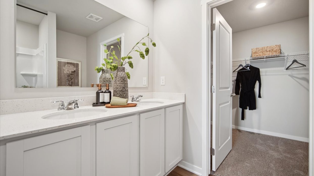 Spacious primary bathroom featuring dual vanities, modern fixtures, and a walk-in shower.