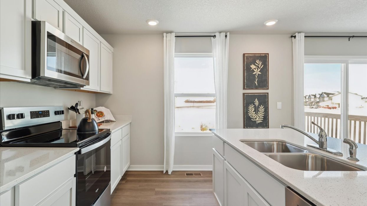Kitchen with stainless steel appliances, quartz countertops, and white cabinetry