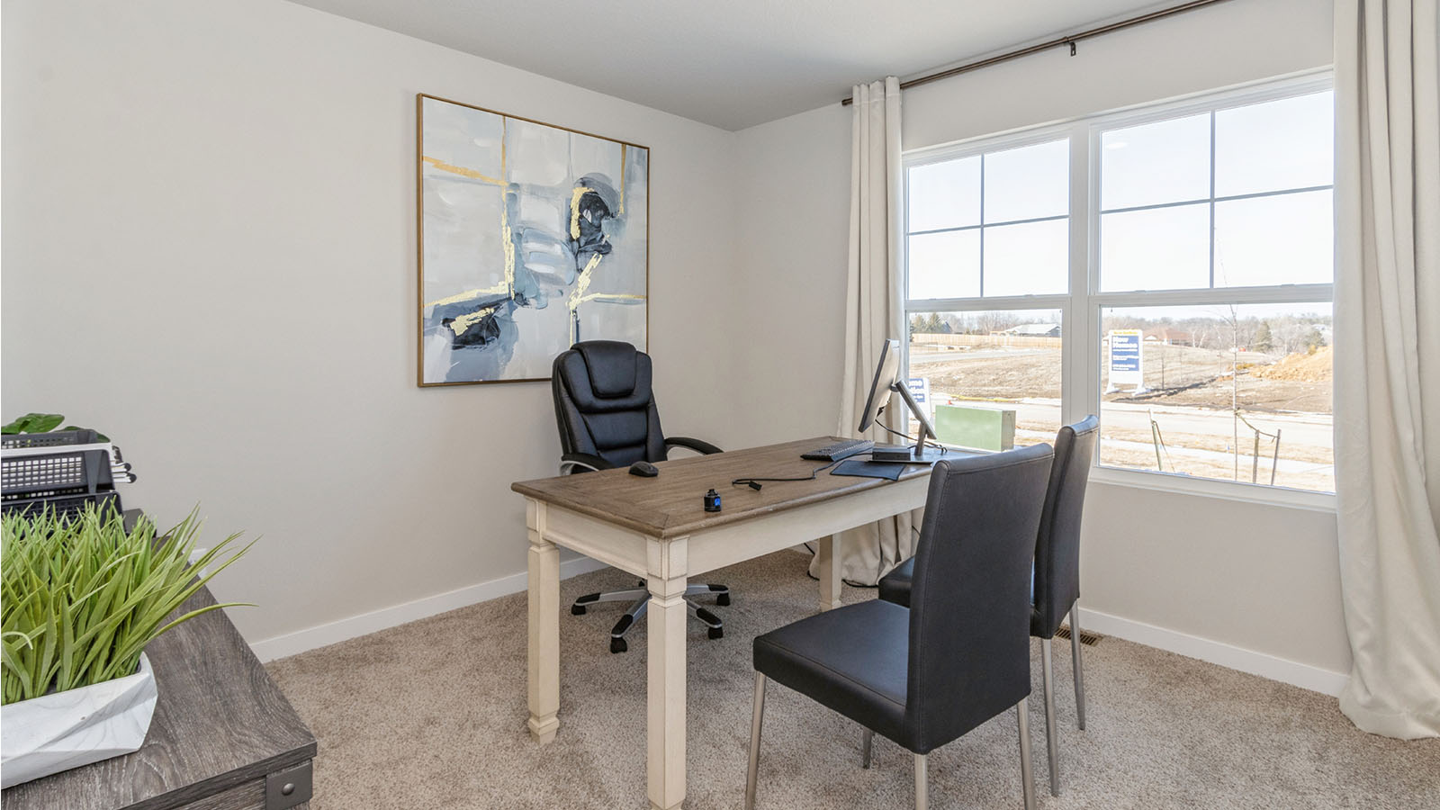 first bedroom at front of the home staged as an office with desk and chairs