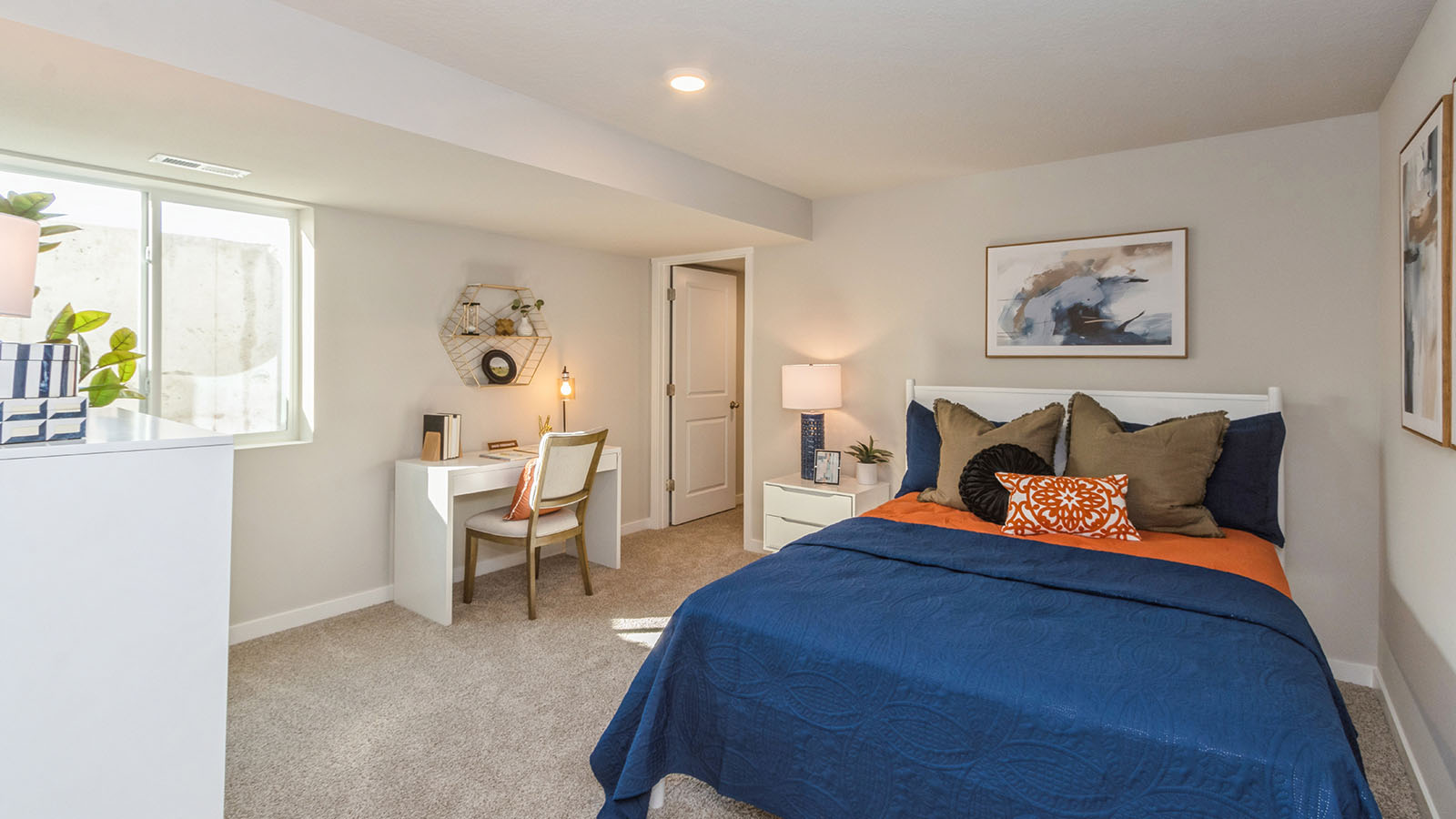 fourth bedroom with blue bed and white dresser and desk with egress window