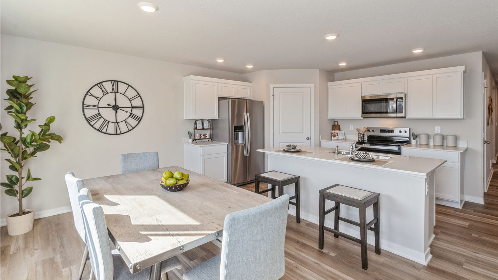 wood dining table with white chairs next to white kitchen