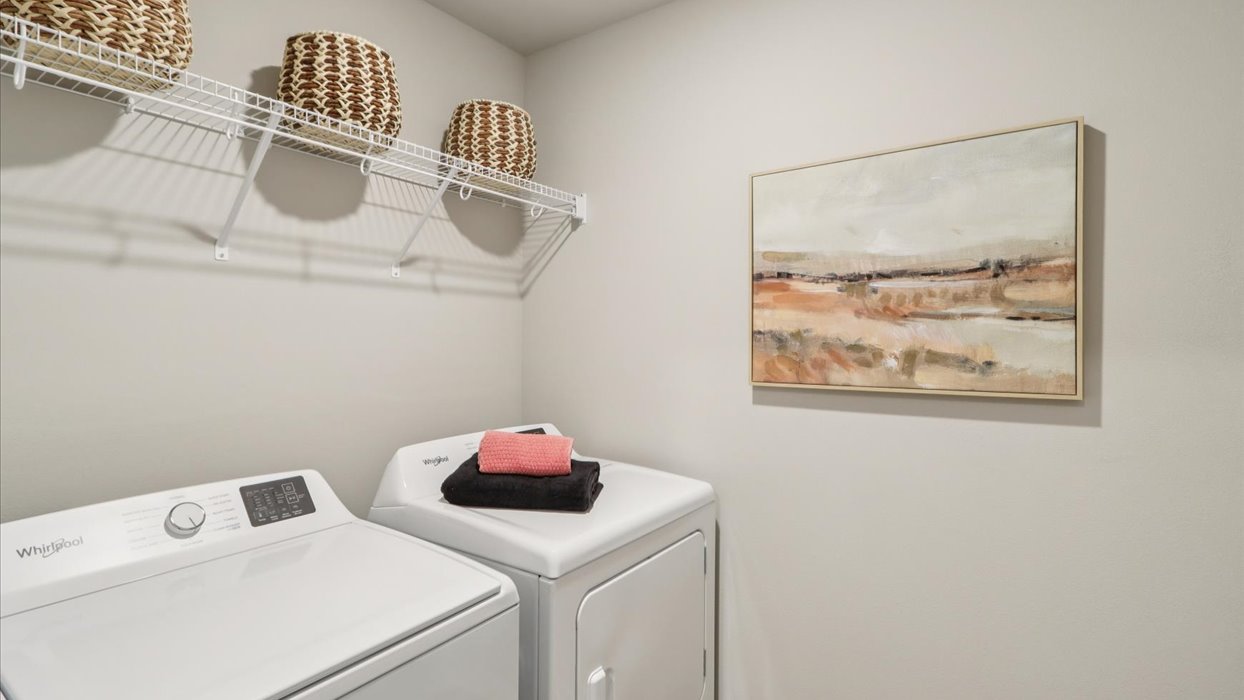 Dedicated laundry room with built-in shelving and utility connections.