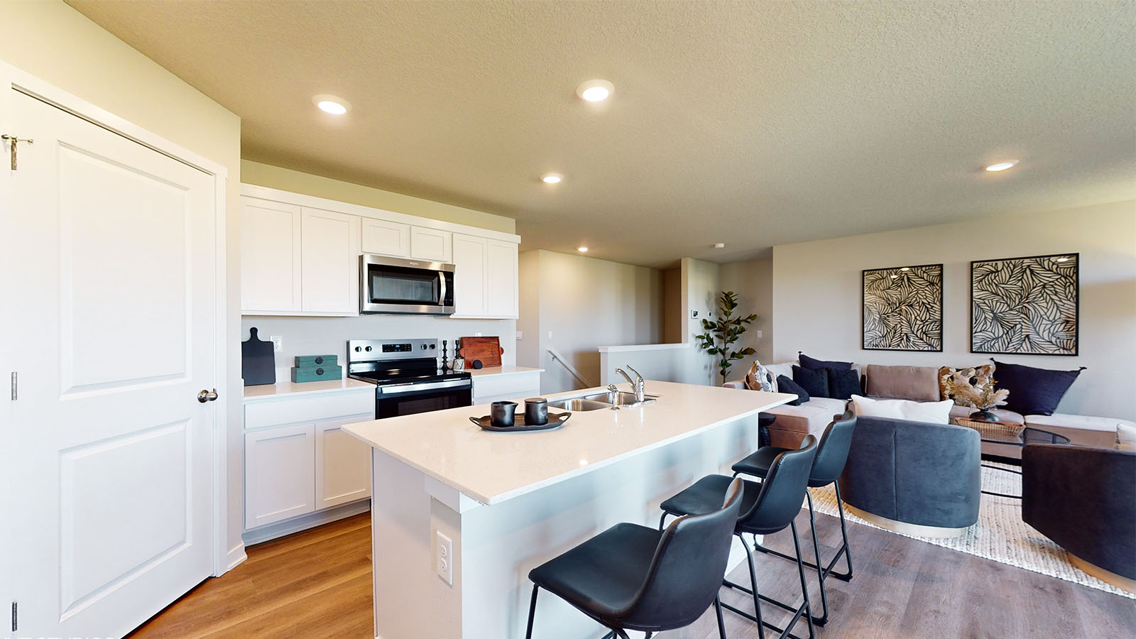 Central kitchen island view adds a sink, seating, pantry, prep zones, with view toward stair access