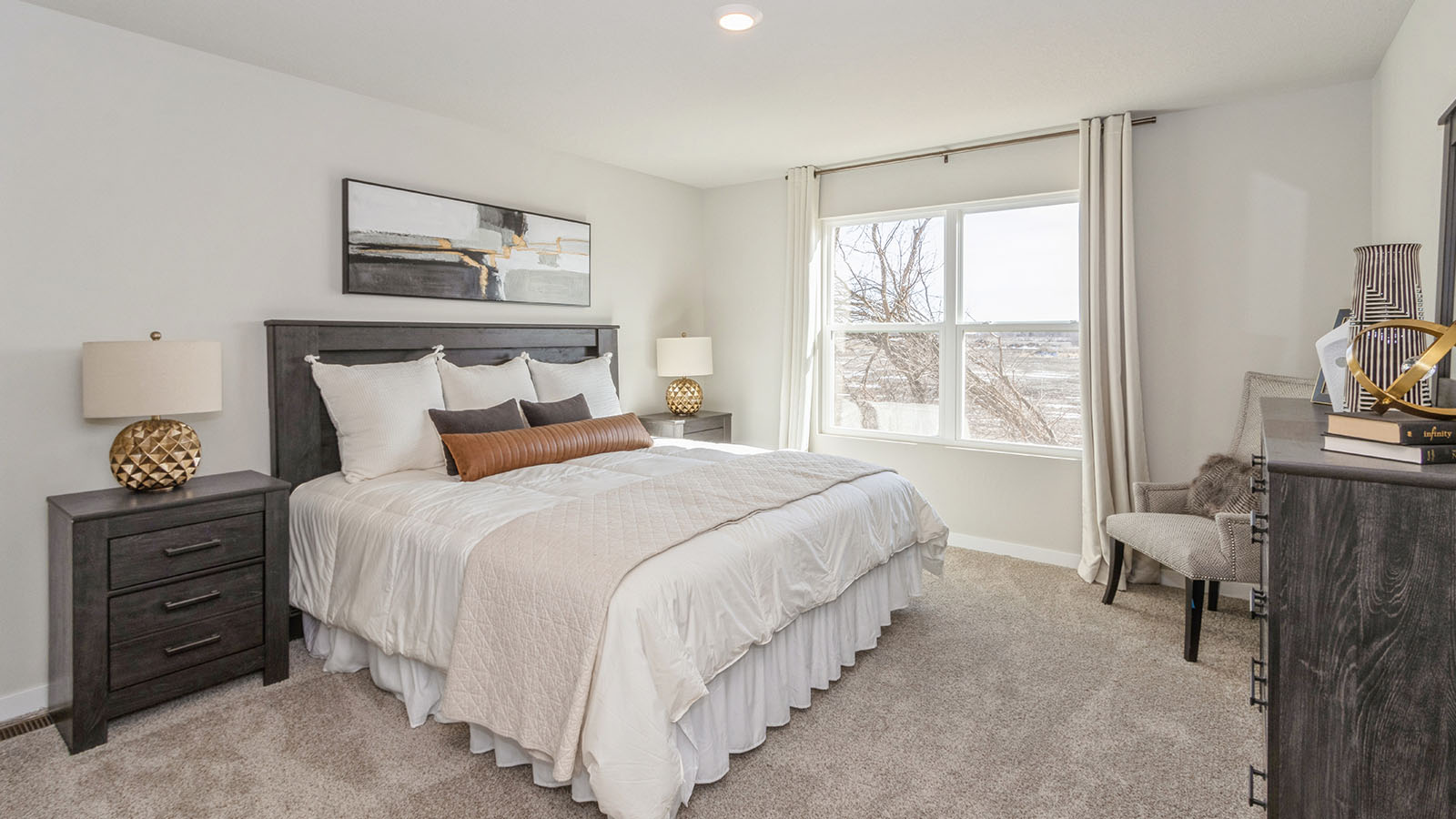 large primary bedroom with large window and wood nighstands and dresser
