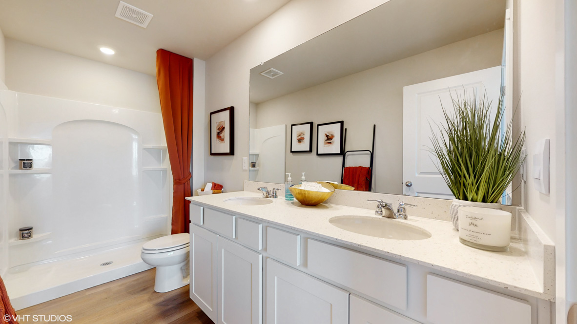 Primary bathroom with a double vanity that features shaker-style cabinetry and quartz countertops and a walk-in shower.