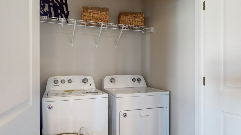 Dedicated laundry room with built-in shelving and utility connections.