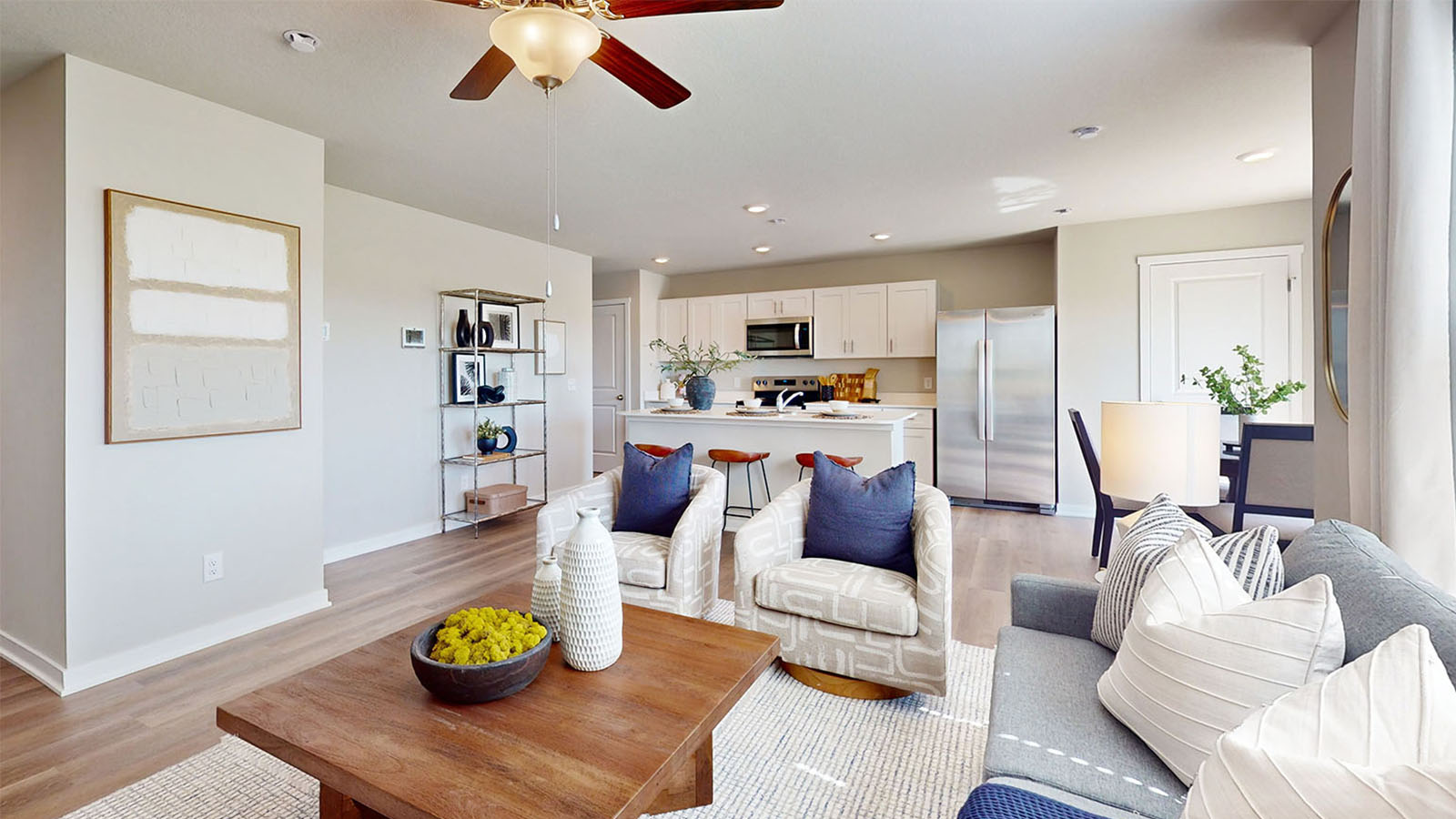 Spacious living room with brown flooring, white walls and windows