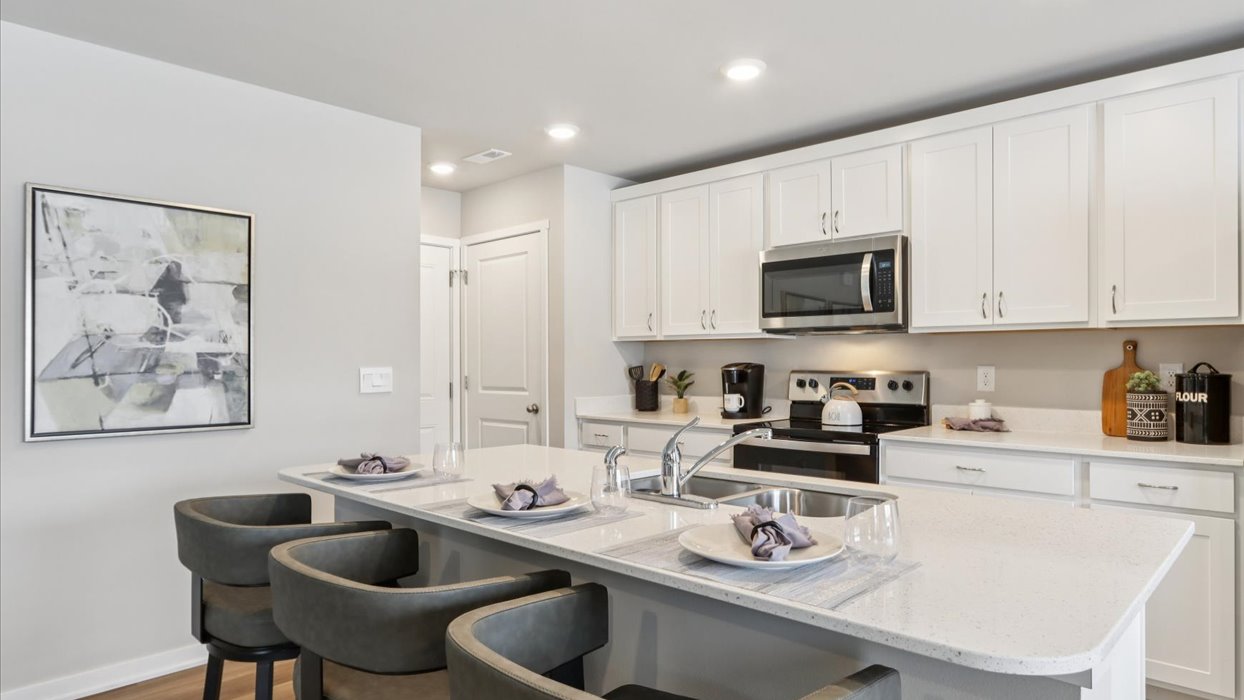 Kitchen with stainless steel appliances, quartz countertops, and white cabinetry