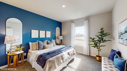 primary bedroom with blue accent wall and small window
