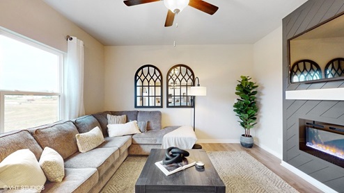 bright living room with black accent wall with ceiling fan