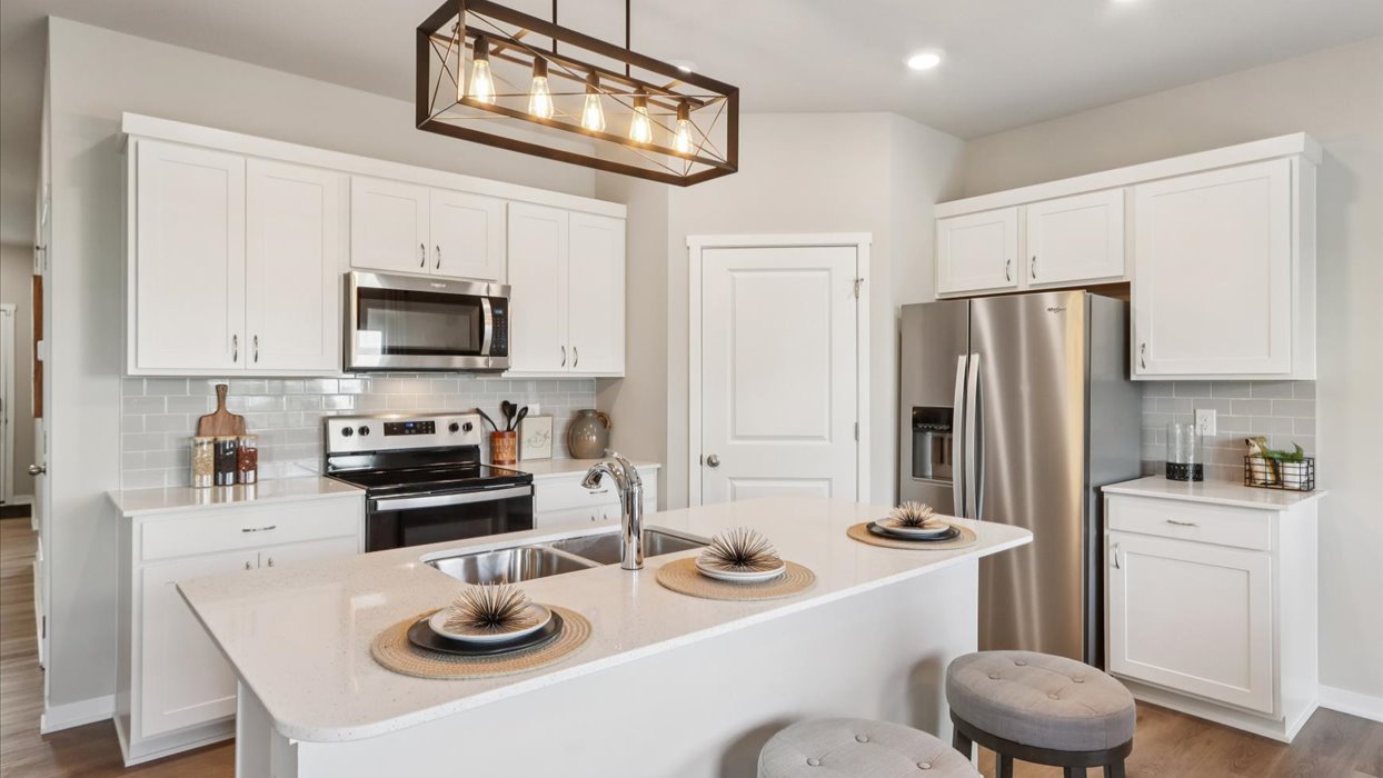 white kitchen with light fixture and stainless-steel appliances