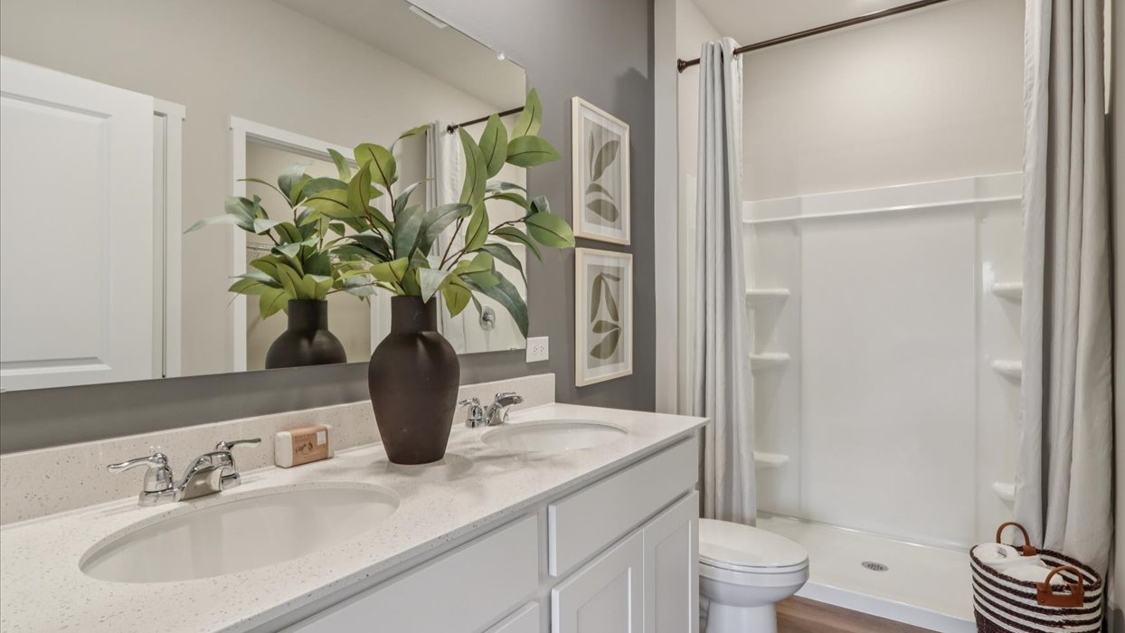 primary bathroom with large mirror and quartz countertops