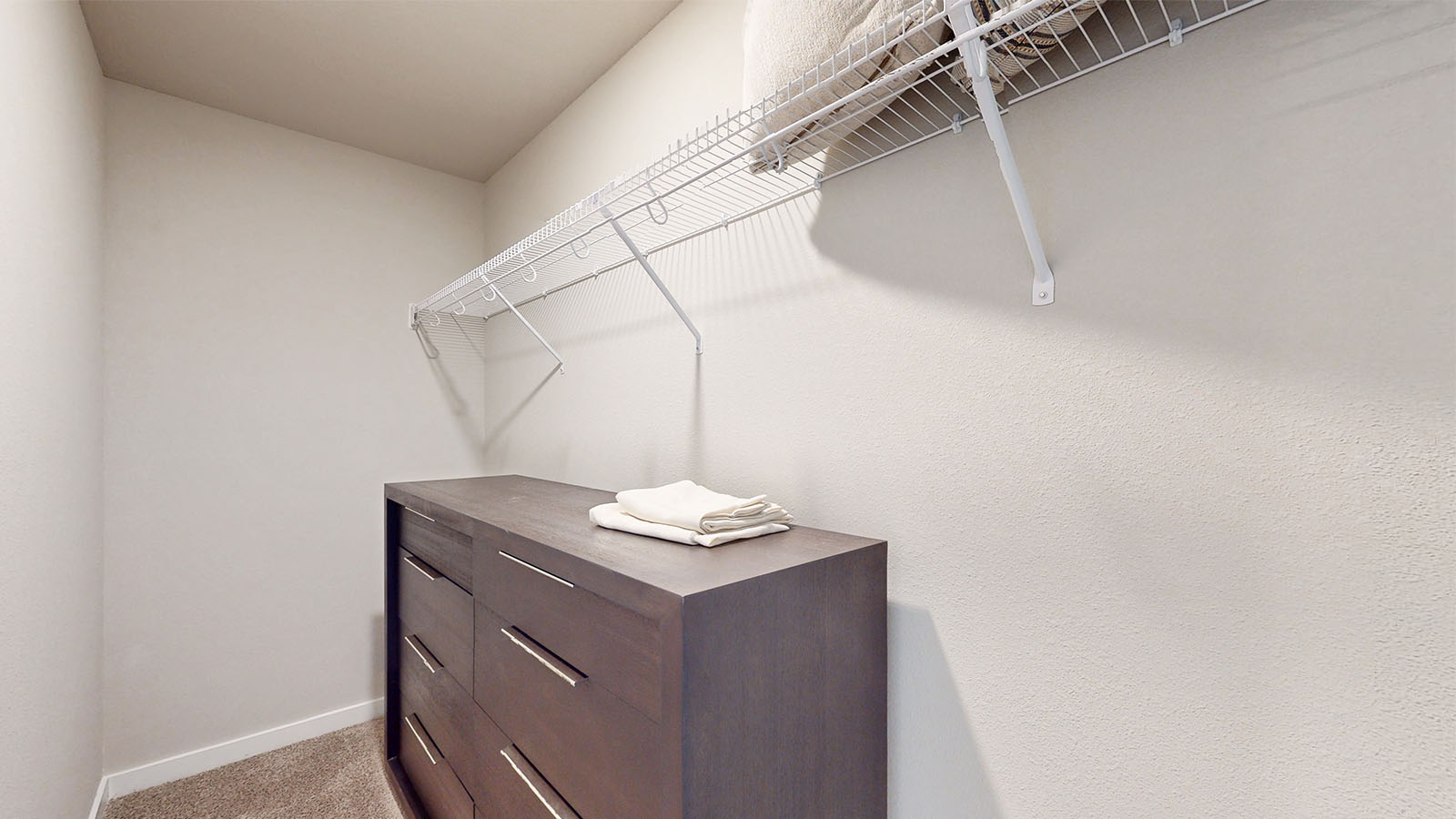 Walk-in closet with shelving and brown dresser
