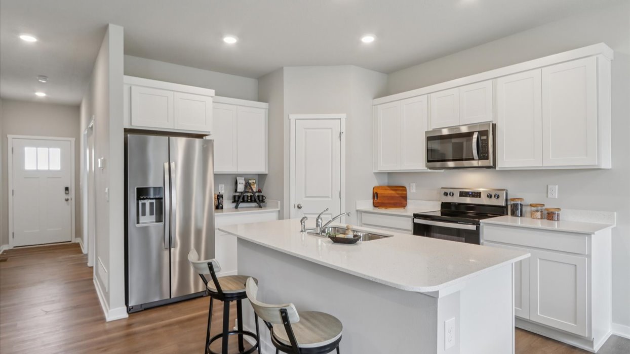 Kitchen with stainless steel appliances, quartz countertops, and white cabinetry
