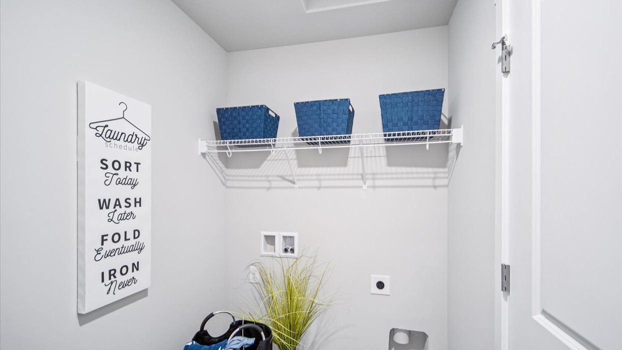 Dedicated laundry room with built-in shelving and utility connections.