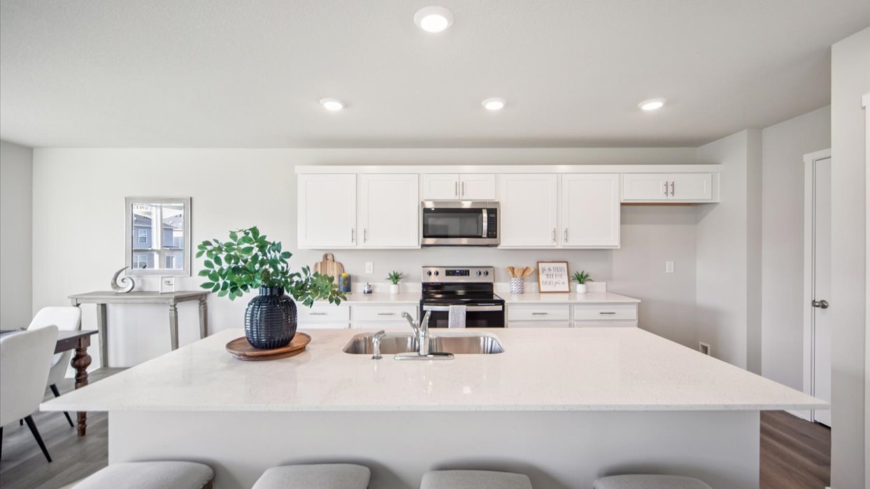 Kitchen with stainless steel appliances, quartz countertops, and white cabinetry