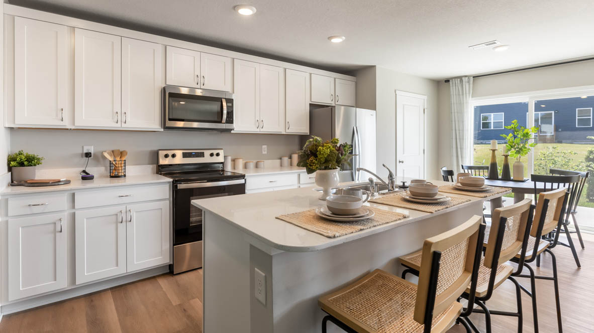 Kitchen with stainless steel appliances, quartz countertops, and white cabinetry