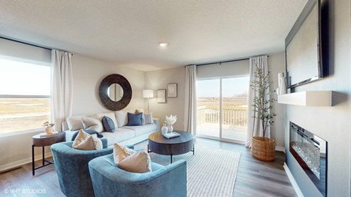 Overview of bright and open living room with fireplace in the abbott model in American prairie