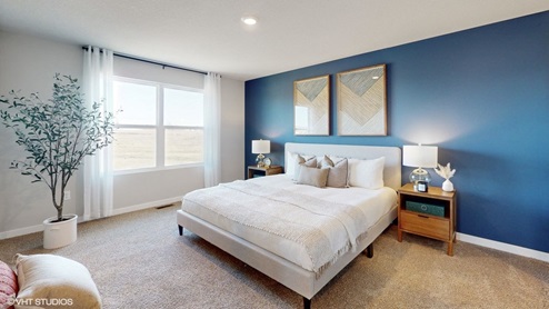 Spacious primary bedroom with window and accent wall