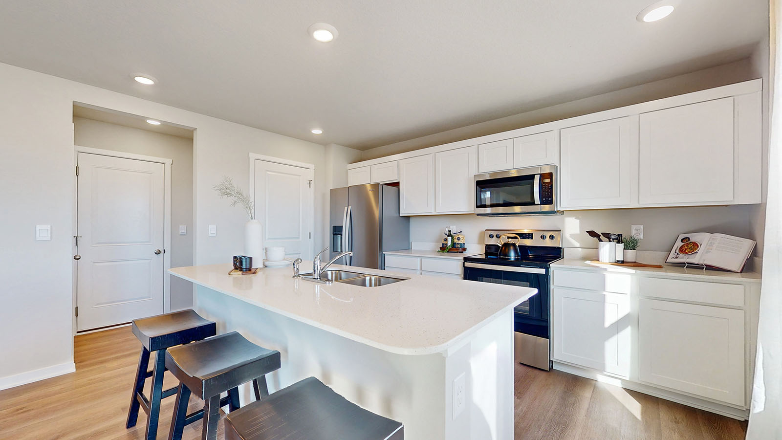 Kitchen with stainless steel appliances, quartz countertops, and white cabinetry