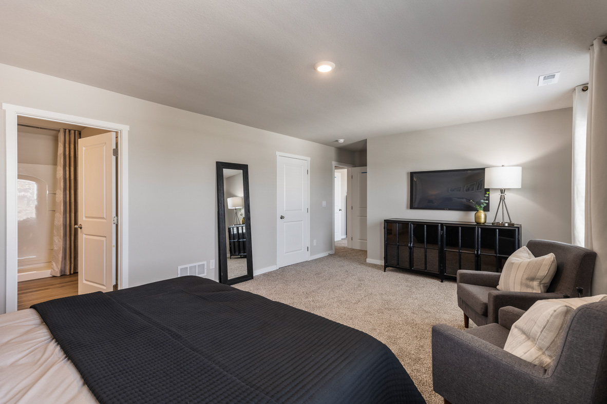 Primary bedroom of the Bellhaven showing the primary bathroom, closet, and seating area