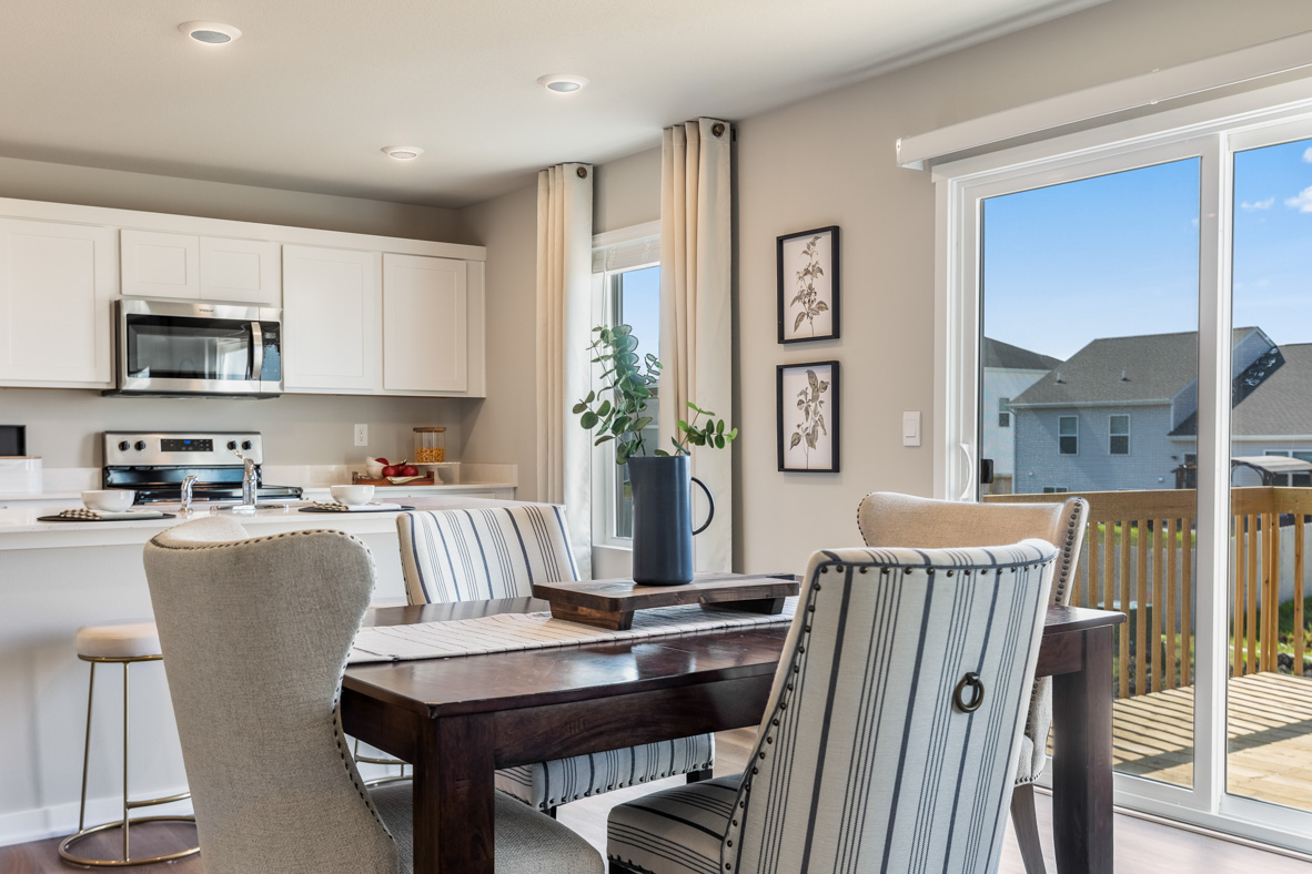 Bellhaven dining room area showing a wooden table with 4 chairs and sliding glass door and kitchen in the background