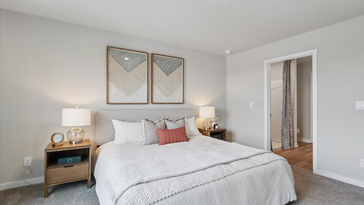 primary bedroom with white bed next to primary bathroom