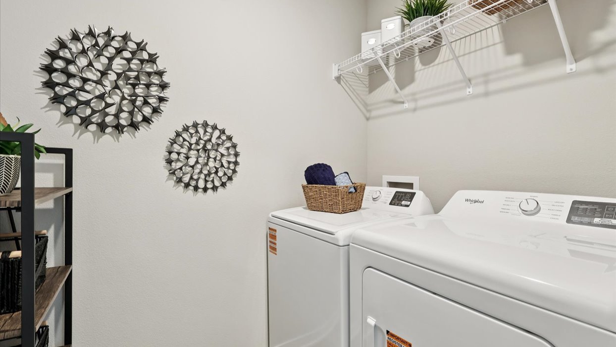 Dedicated laundry room with built-in shelving and utility connections.