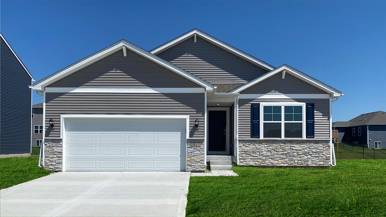 Exterior photo a one-story home with horizontal plank siding, stone and a two-car garage.