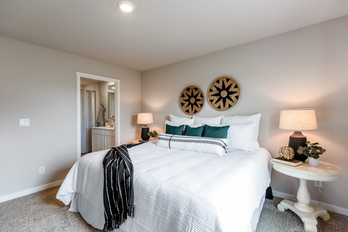 Looking past the large bed and two nightstands in the Roland's primary bedroom towards the attached primary bathroom.