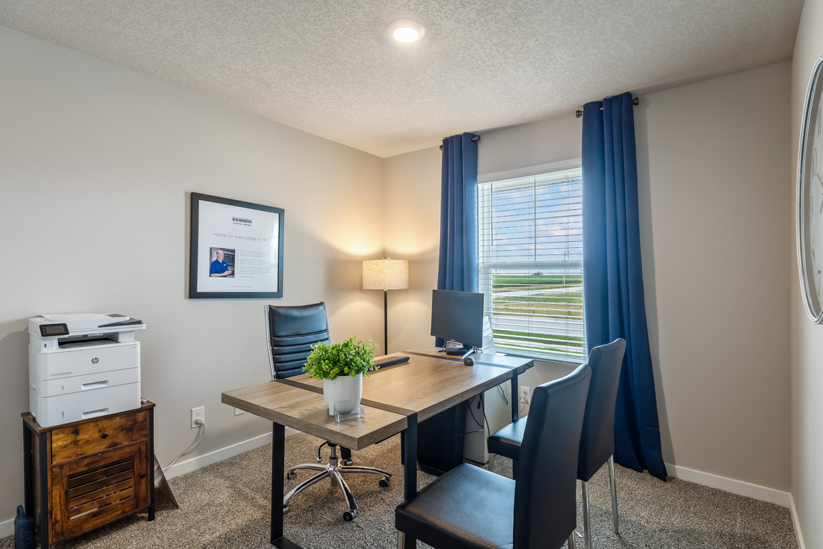 Fourth bedroom in the Roland outfitted as an office with a desk, desk chair, two guest chairs, and other office equipment.