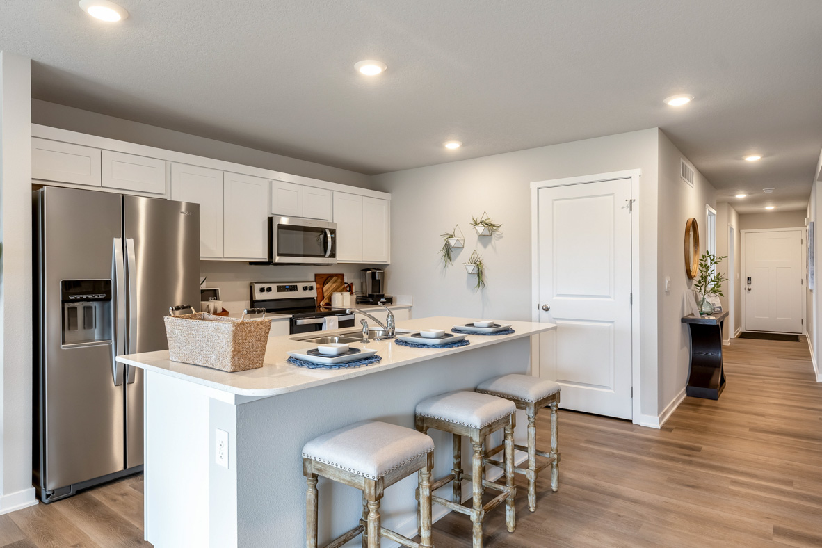 Kitchen with white, shaker-style cabinetry, stainless-steel appliances, and white, quartz countertops in the Roland.