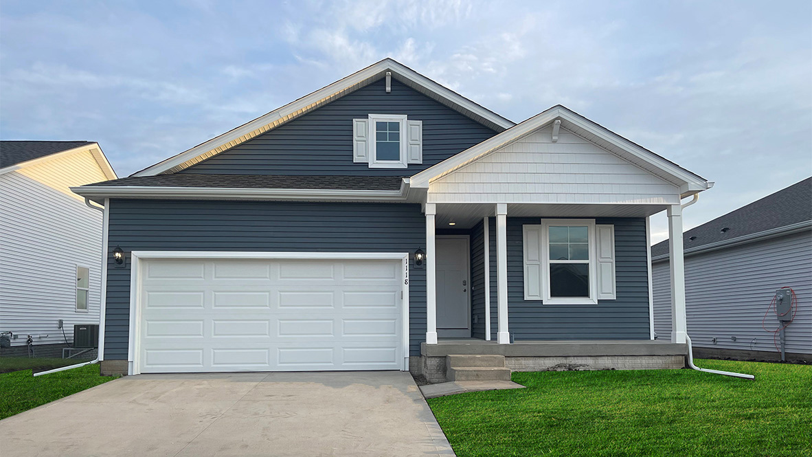 Exterior photo of the Roland floorplan with midnight blue siding and a covered front porch and a two-car garage