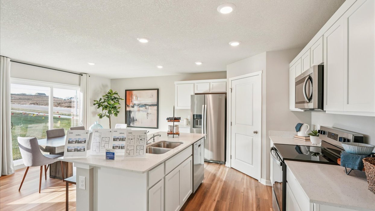 Kitchen with stainless steel appliances, quartz countertops, and white cabinetry