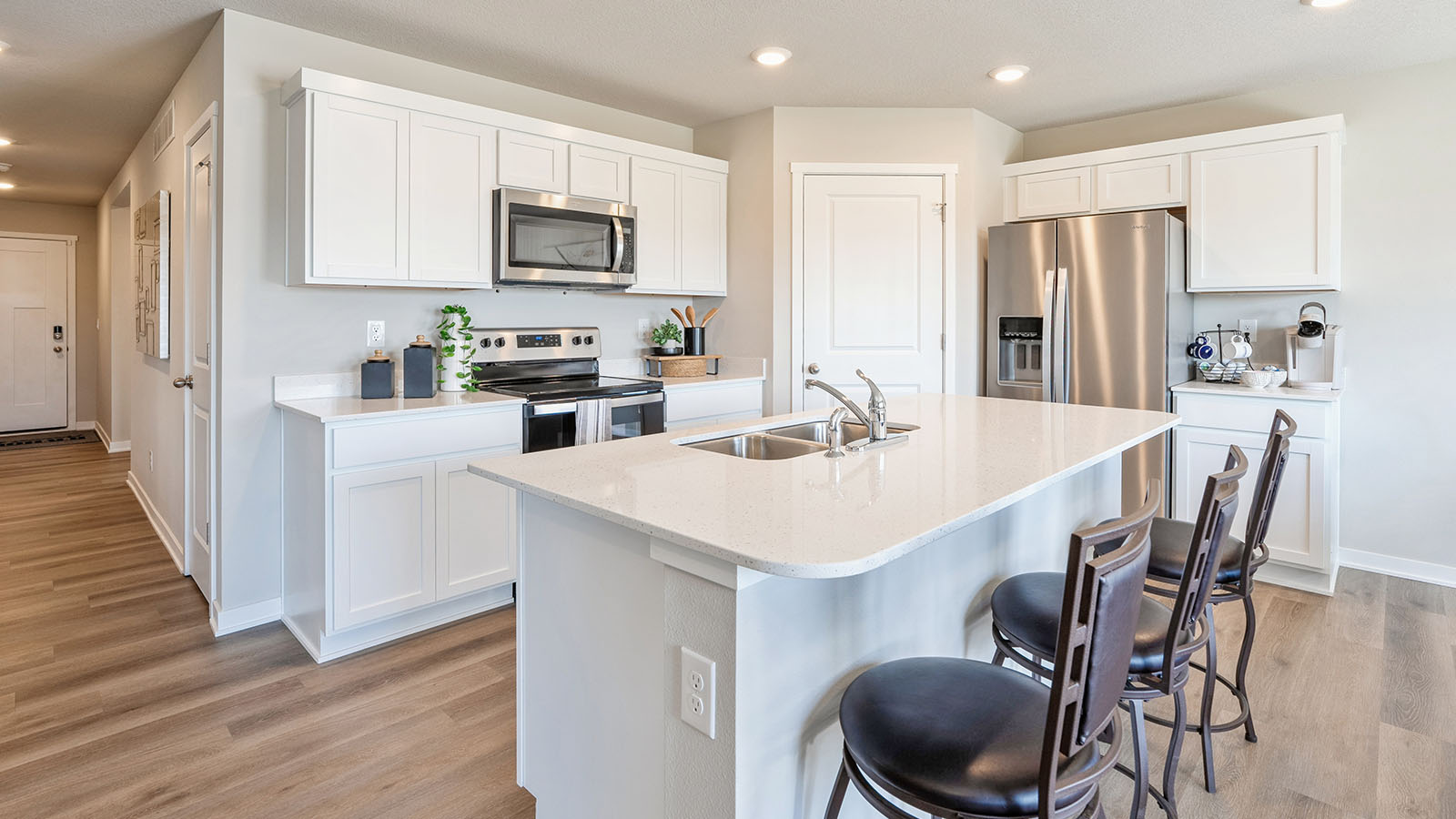 Kitchen with stainless steel appliances, quartz countertops, and white cabinetry