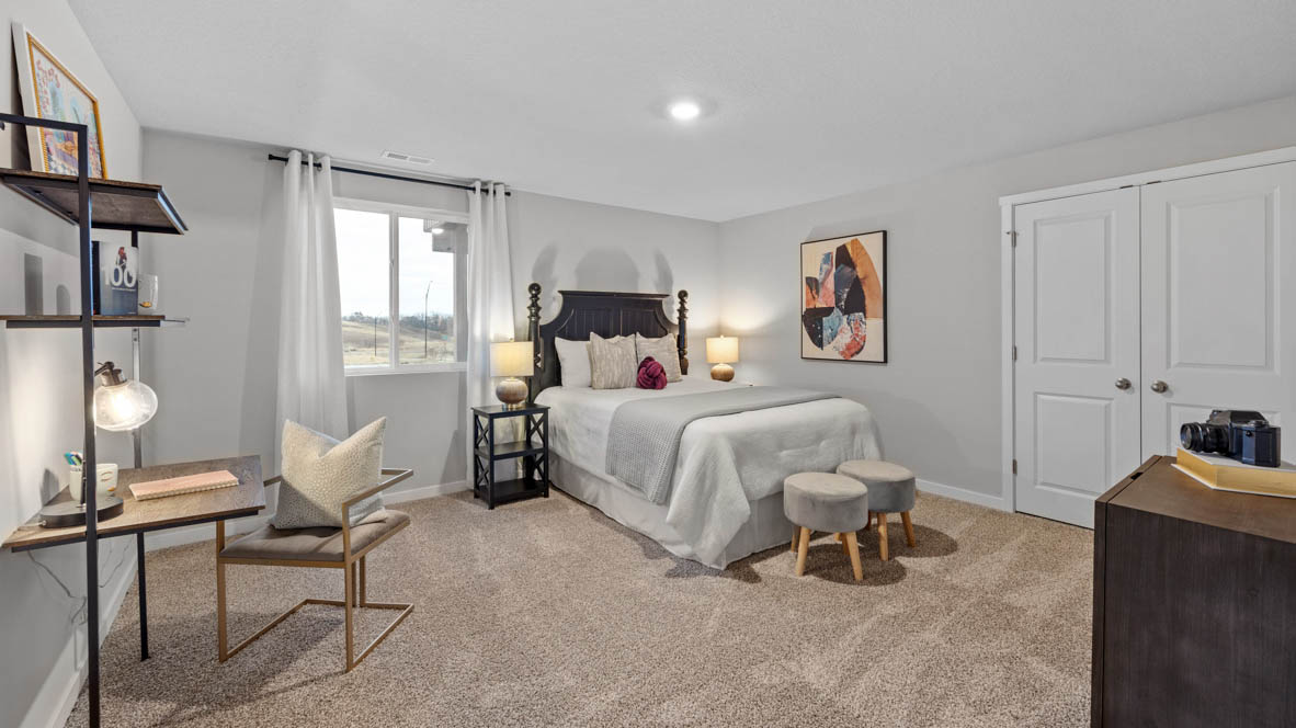 Second bedroom in basement with white bed and black desk