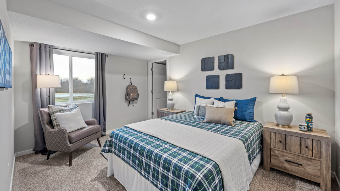 Third bedroom in basement with blue bed and brown nightstands