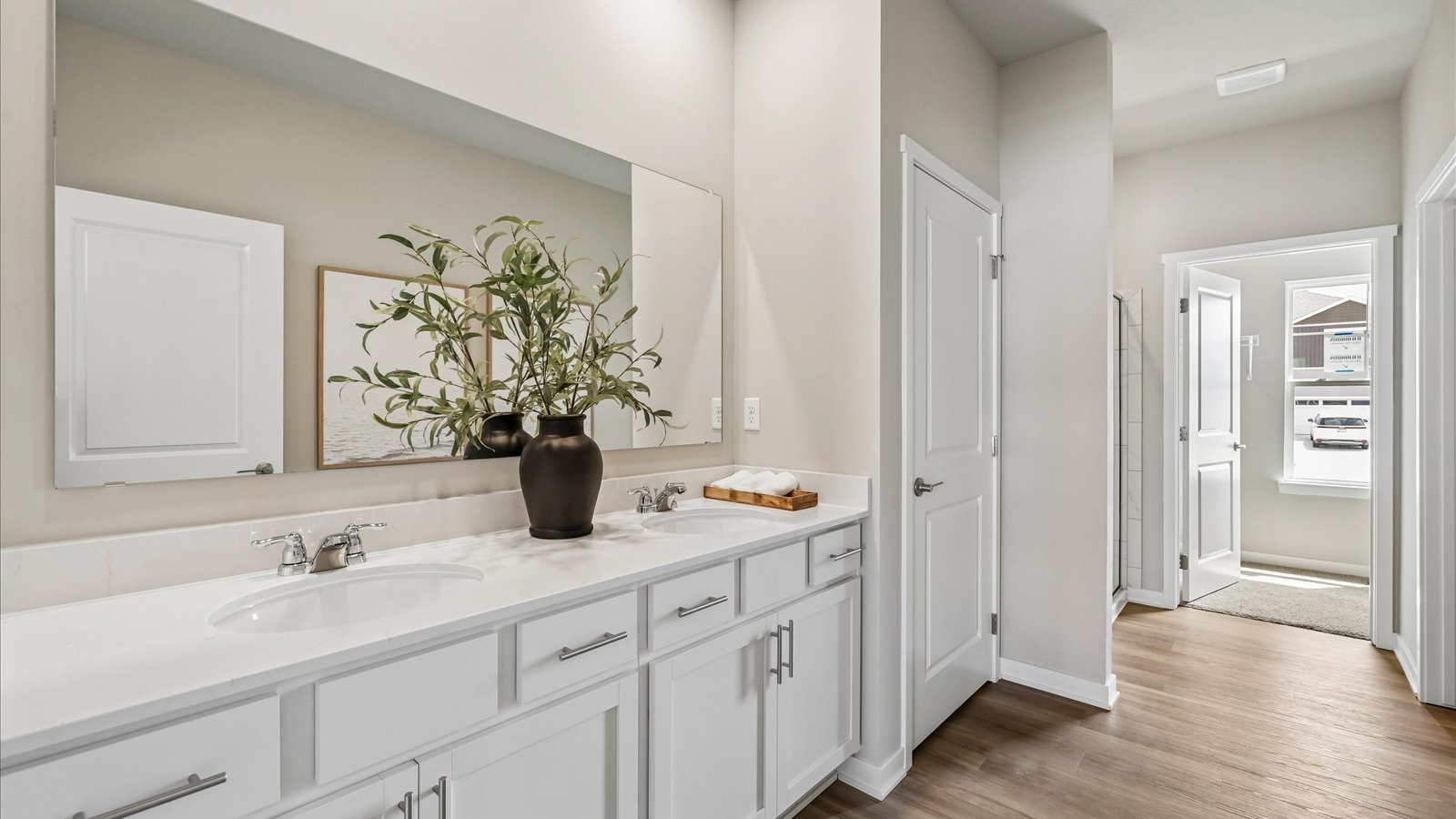Spacious primary bathroom featuring dual vanities, modern fixtures, and a walk-in shower.
