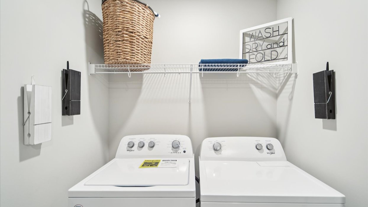 Cozy laundry space with natural light, a washer and dryer, and shelving for supplies.