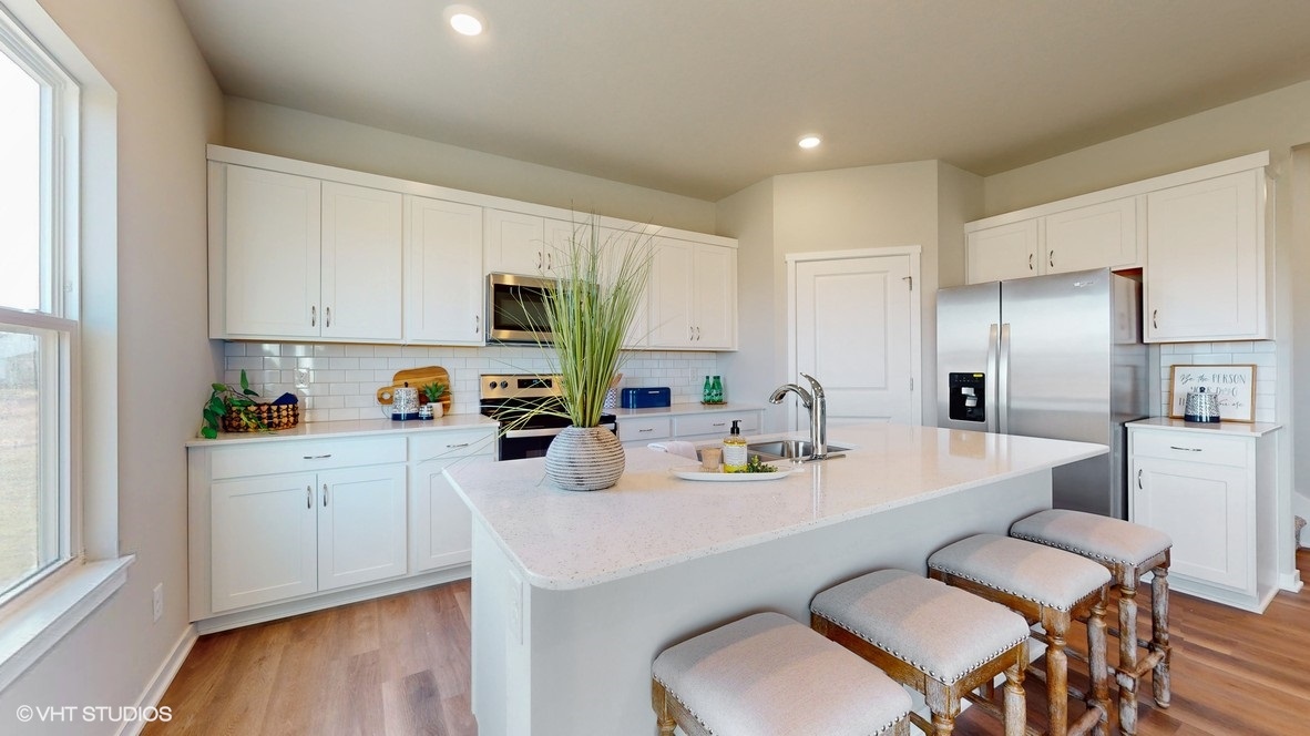 Kitchen with stainless steel appliances, quartz countertops, and white cabinetry