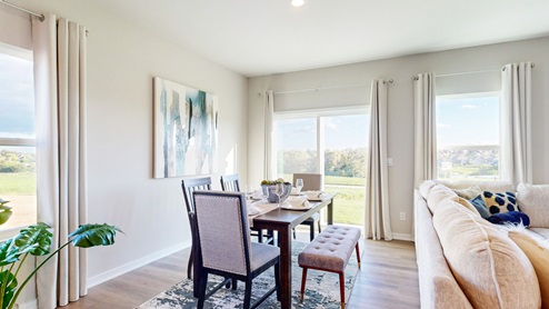 Wooden dining table surrounded by four chairs and a bench seat in front of sliding glass doors that provide access to the back yard.