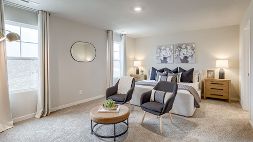Big primary bedroom with two large windows king bed and seating area
