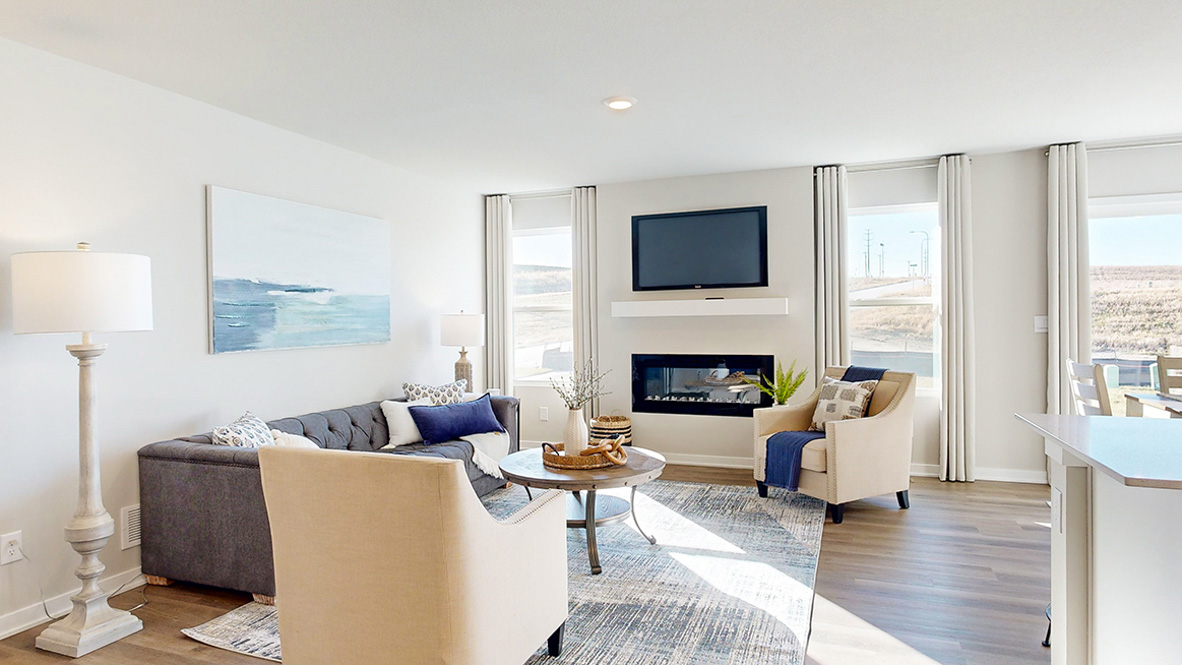 Bright living room with electric fireplace, direct connection to dining nook and kitchen island in this New build House