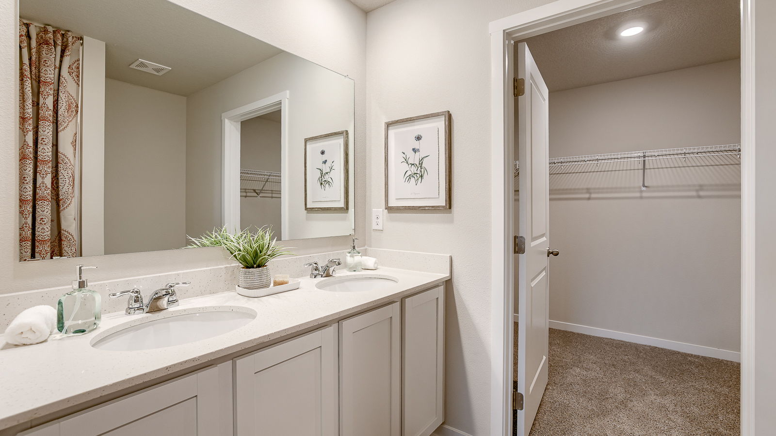 Primary bathroom in the Hamilton showcasing dual sinks and primary walk-in closet