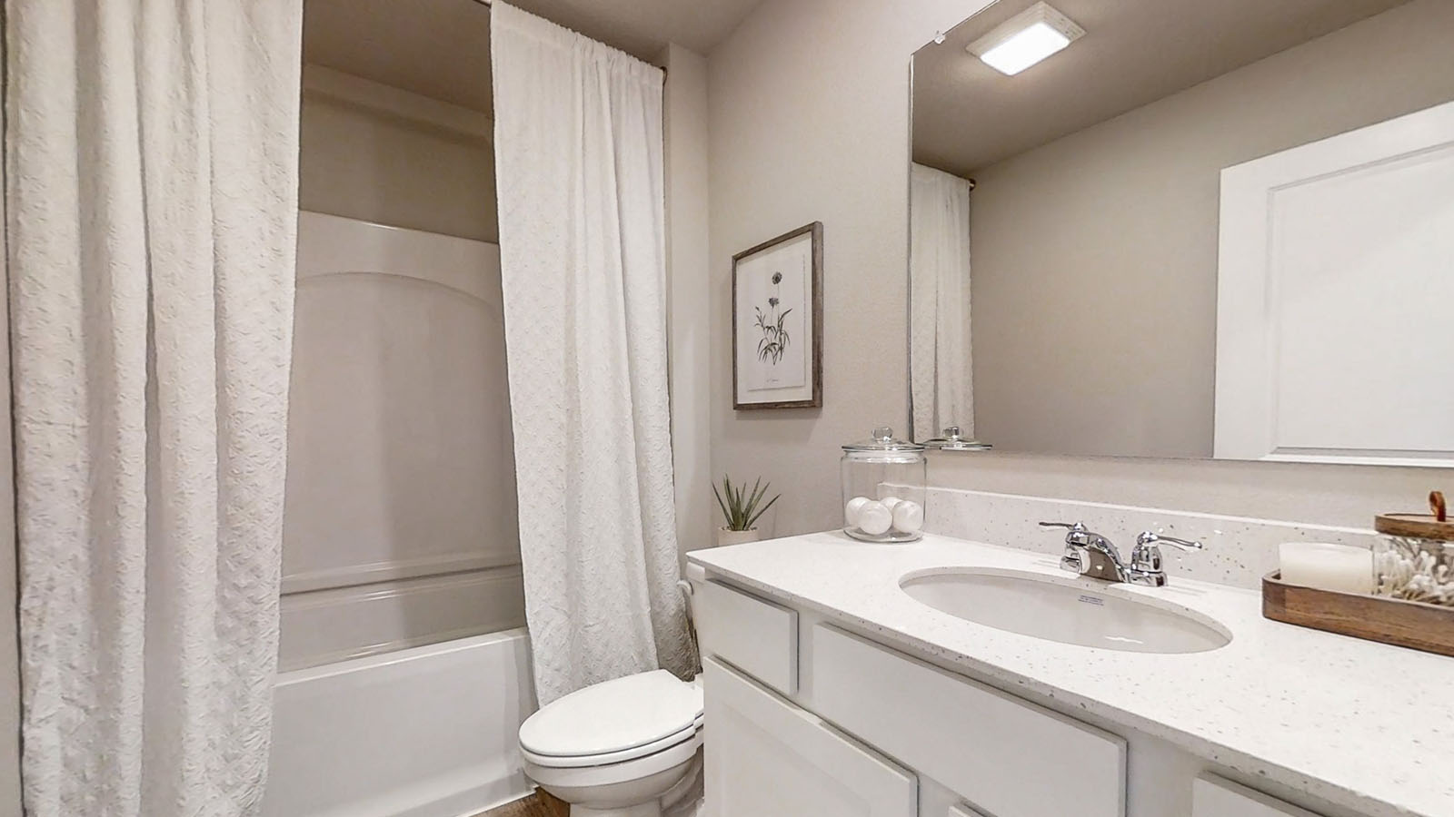 Sleek family-guest bath with single sink, mirror, cabinets, and shower-tub combination at Quail Ranch