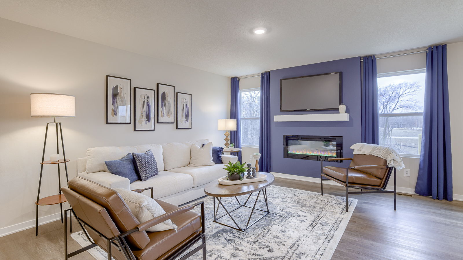 Main level living room offers a bright space with electric fireplace and open concept connections to kitchen and living spaces