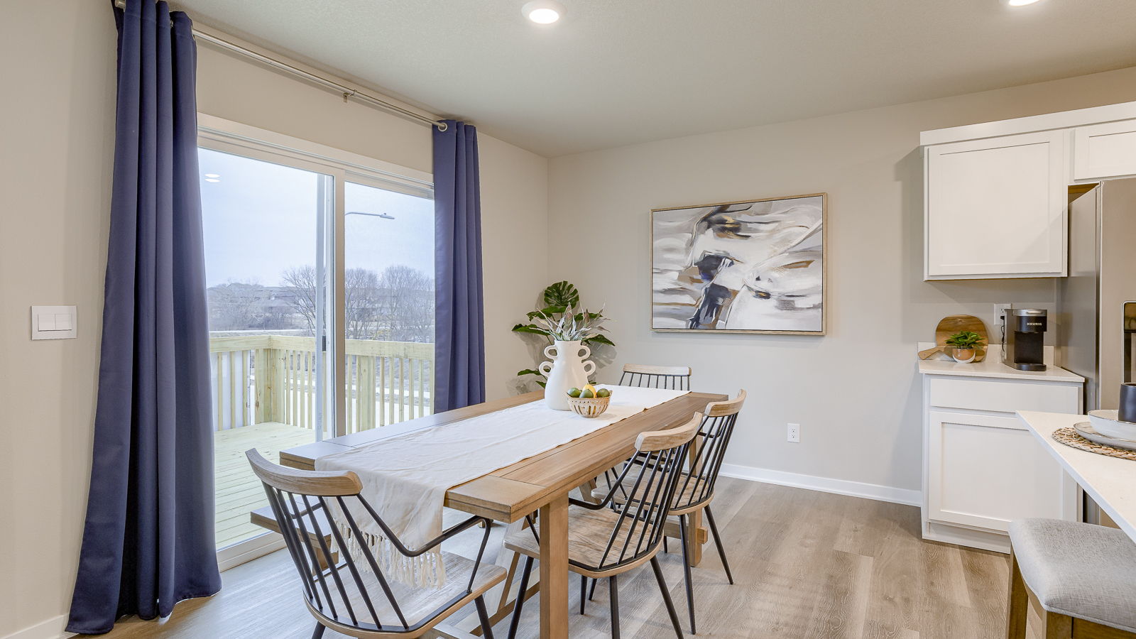 Dining room near electric fireplace, natural light, and seamless flow into kitchen and outdoor access