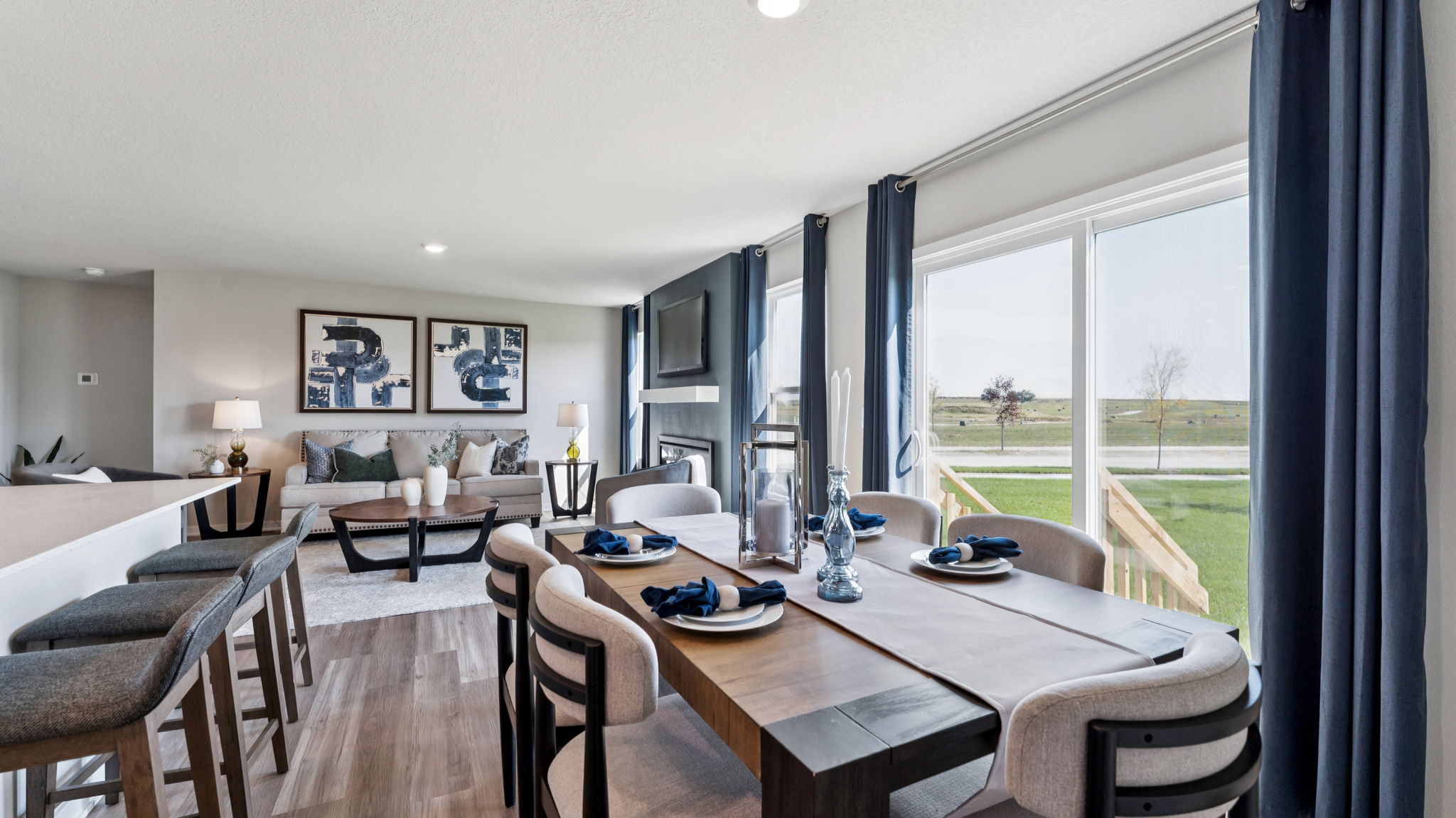 View of living and dining area of the Hamilton with large dining table and sliding glass window to back pation