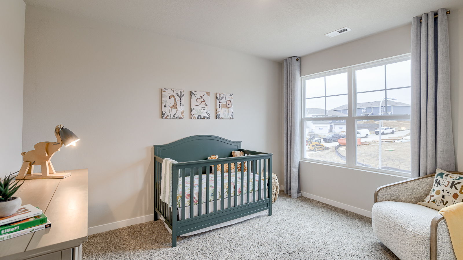 Fourth bedroom staged as a nursery with a crib and chair and natural lighting