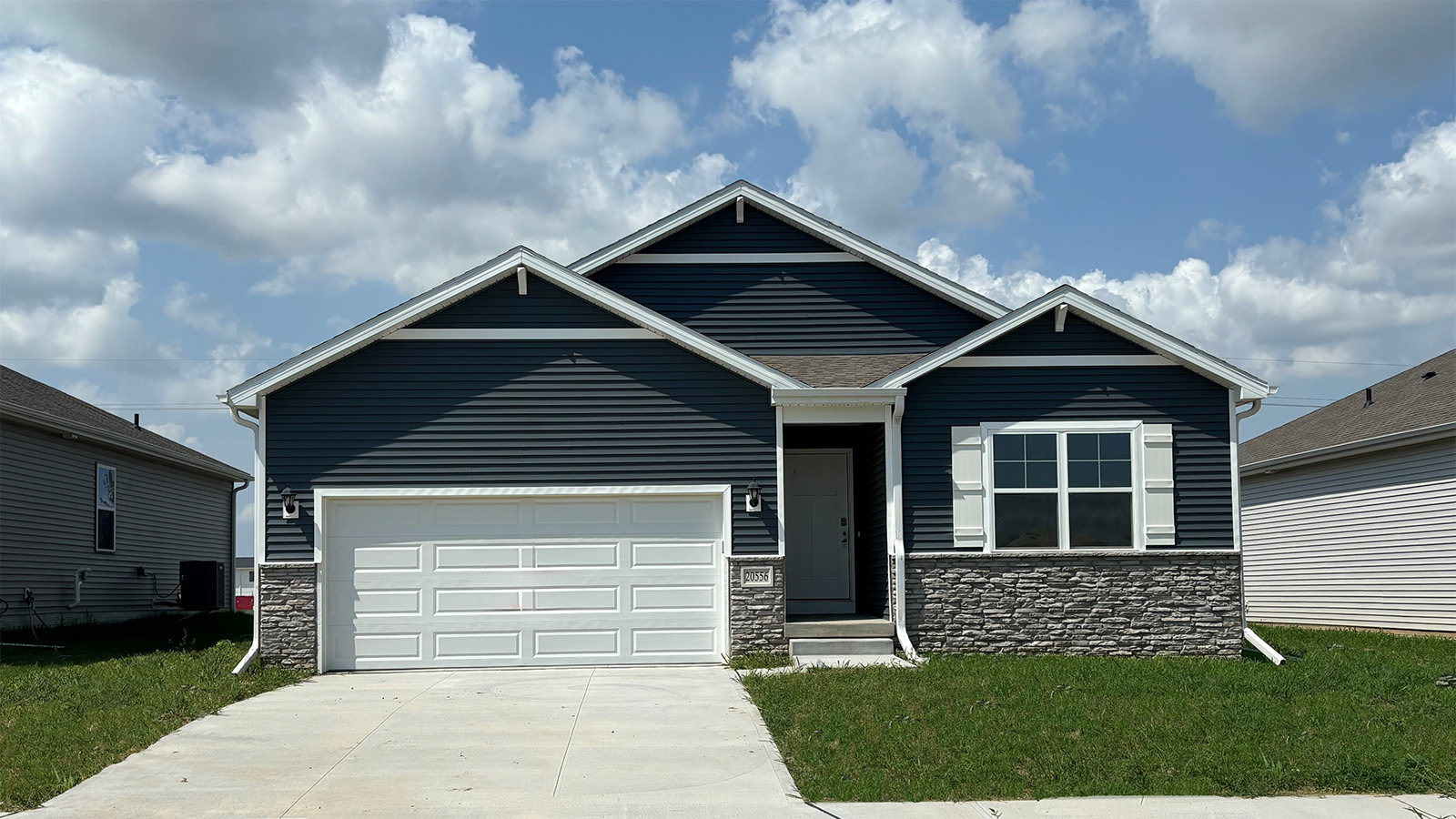 exterior of the Neuville with blue siding, stone and 2 car garage